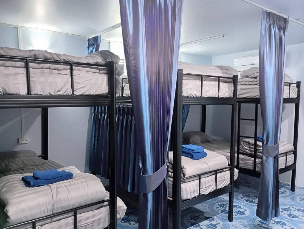 a room with four bunk beds with blue curtains at SK Hometel Samui Airport in Bang Rak Beach