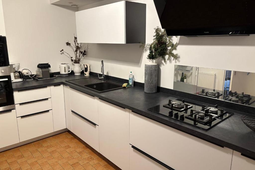 a kitchen with white cabinets and a black counter top at Maison les dunes proche plage in Quiberon