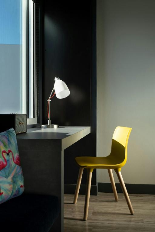 a yellow chair sitting next to a desk with a lamp at Aloft Sarasota in Sarasota