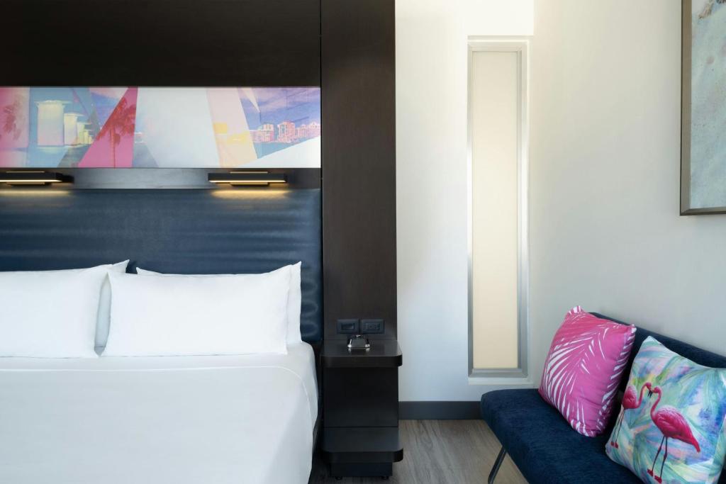 a bedroom with a bed and a blue couch at Aloft Sarasota in Sarasota