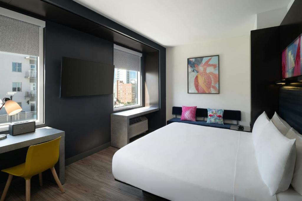 a bedroom with a large white bed and a desk at Aloft Sarasota in Sarasota
