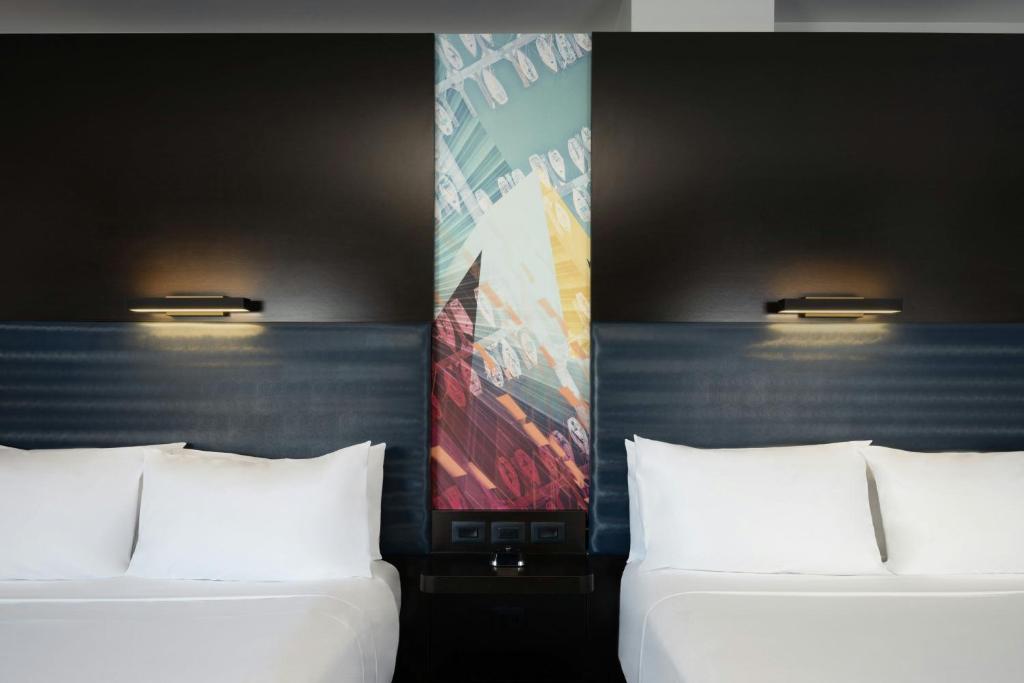 two beds with white pillows in a room at Aloft Sarasota in Sarasota