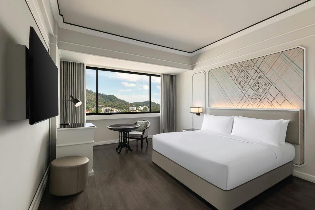 a bedroom with a white bed and a table at Courtyard by Marriott Phuket Town in Phuket Town