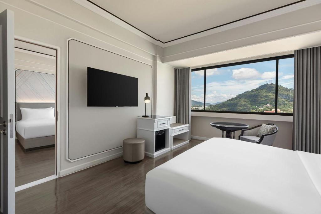 a hotel room with a bed and a large window at Courtyard by Marriott Phuket Town in Phuket Town