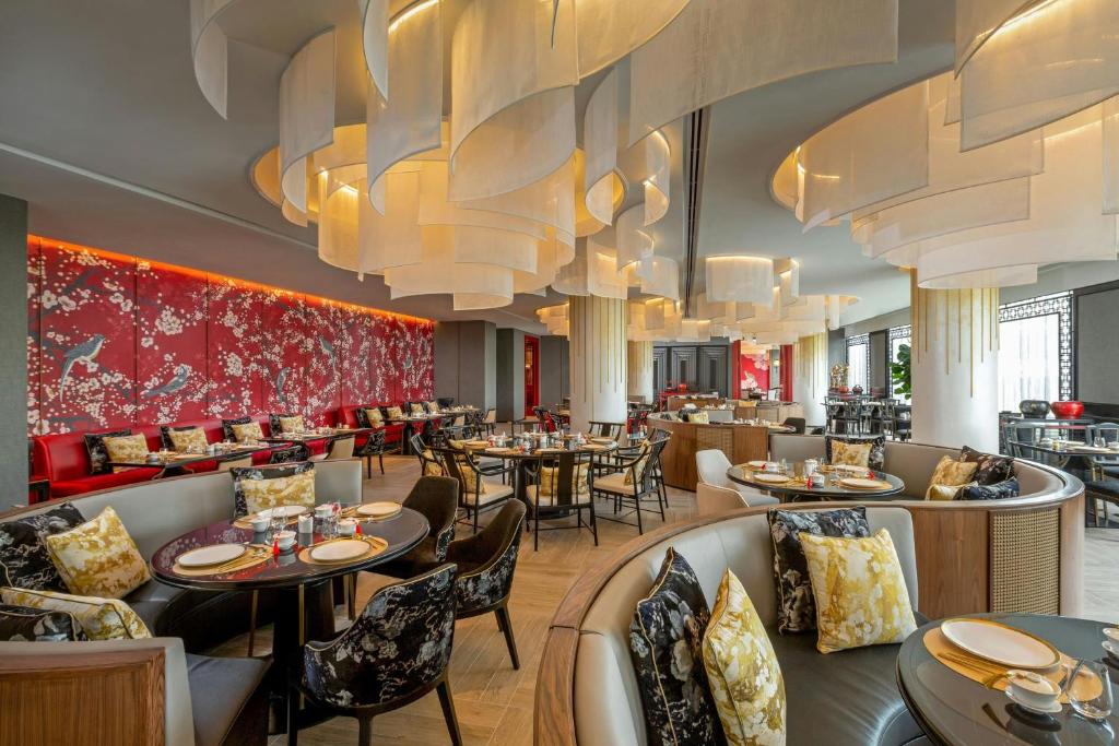 a restaurant with tables and chairs and chandeliers at Courtyard by Marriott Phuket Town in Phuket Town