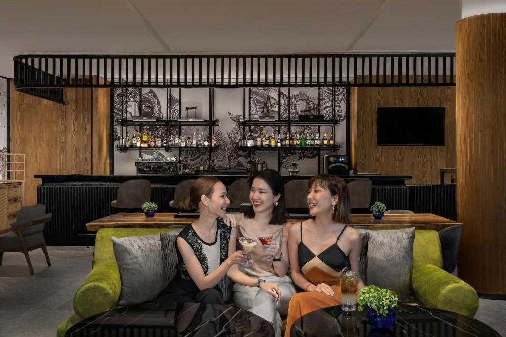 three women sitting on a couch in a bar at Courtyard by Marriott Phuket Town in Phuket Town