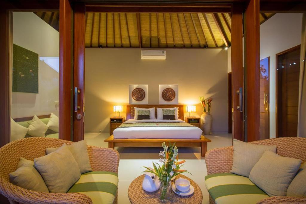 a bedroom with a bed and two wicker chairs at Villa Green Manggo Seminyak Bali in Seminyak