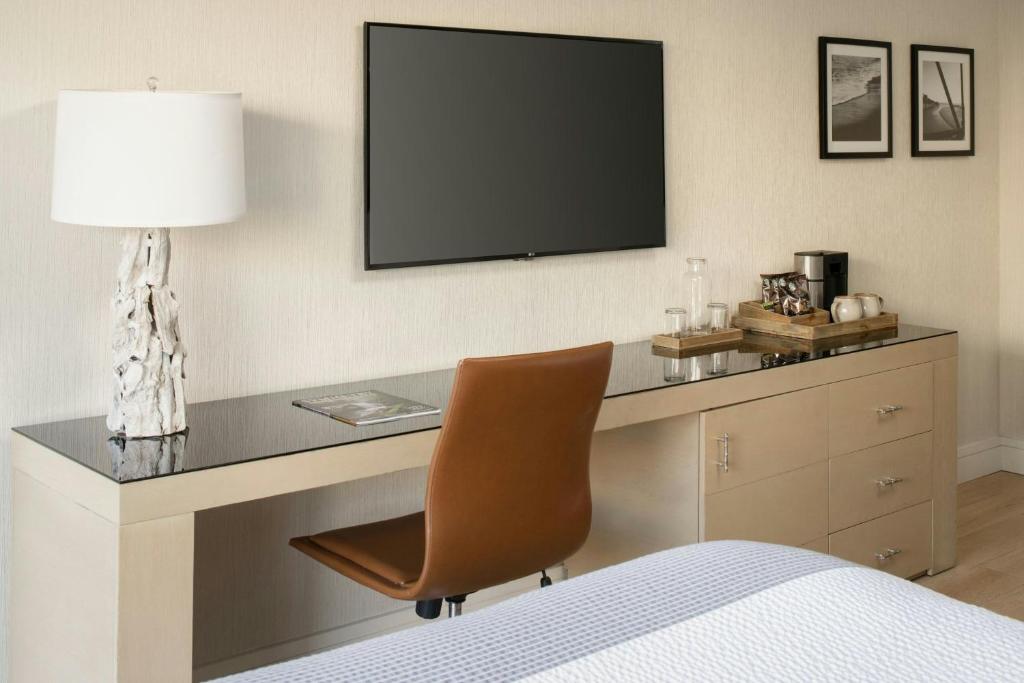 a bedroom with a desk with a television and a chair at Hotel Paradox, Autograph Collection in Santa Cruz