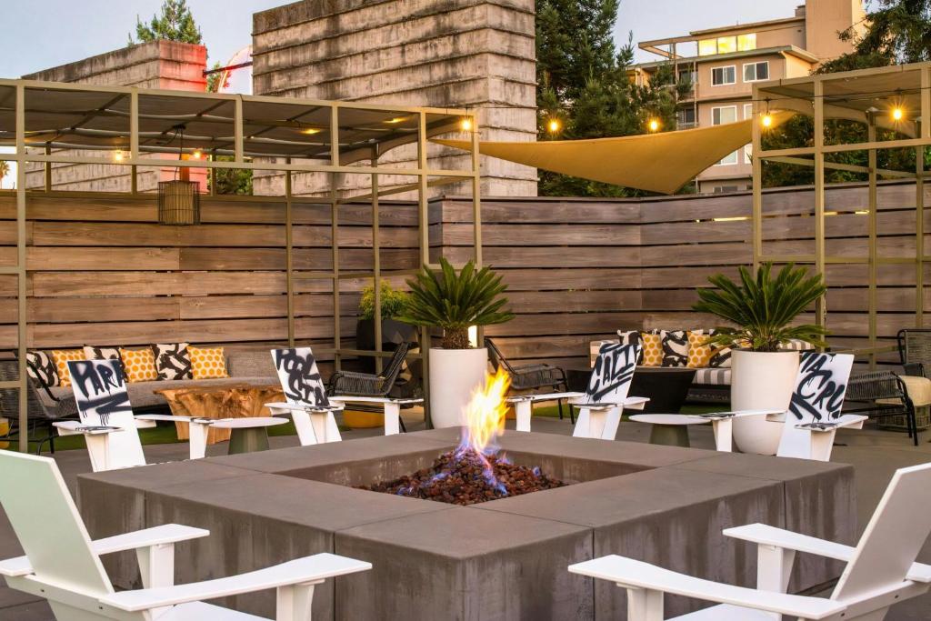 a fire pit in a patio with white chairs at Hotel Paradox, Autograph Collection in Santa Cruz