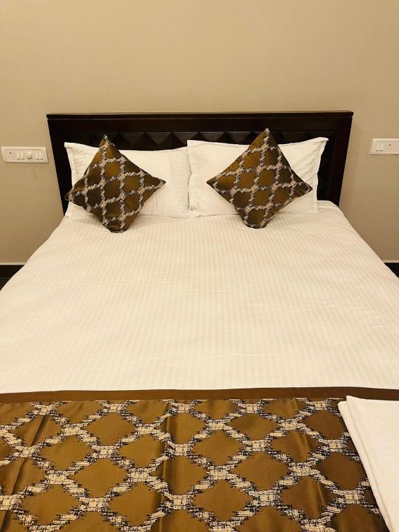 a bed with brown and white sheets and pillows at The Forest Grove by Living Circle in Yelagiri