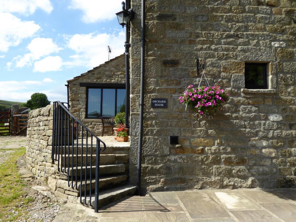 a stone building with a staircase and flowers on it at Orchard House Bed and Breakfast in Grassington