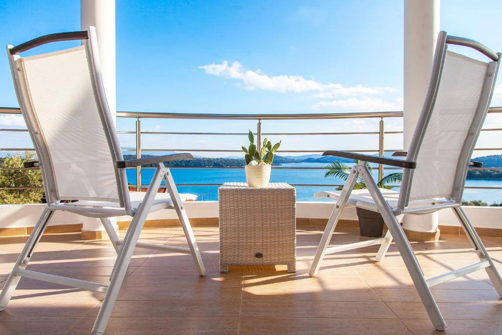 twee witte stoelen op een balkon met een plant bij Villa Maria PF in Nydri