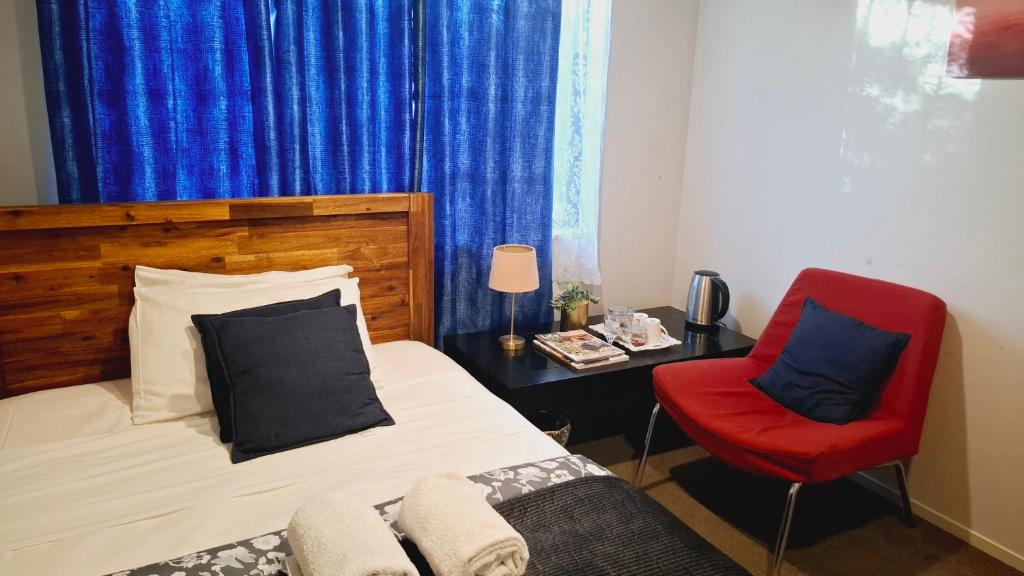 Un dormitorio con una cama y una silla roja. en Modern Sunny & Comfy Rooms near Henderson, Auckland, en Auckland