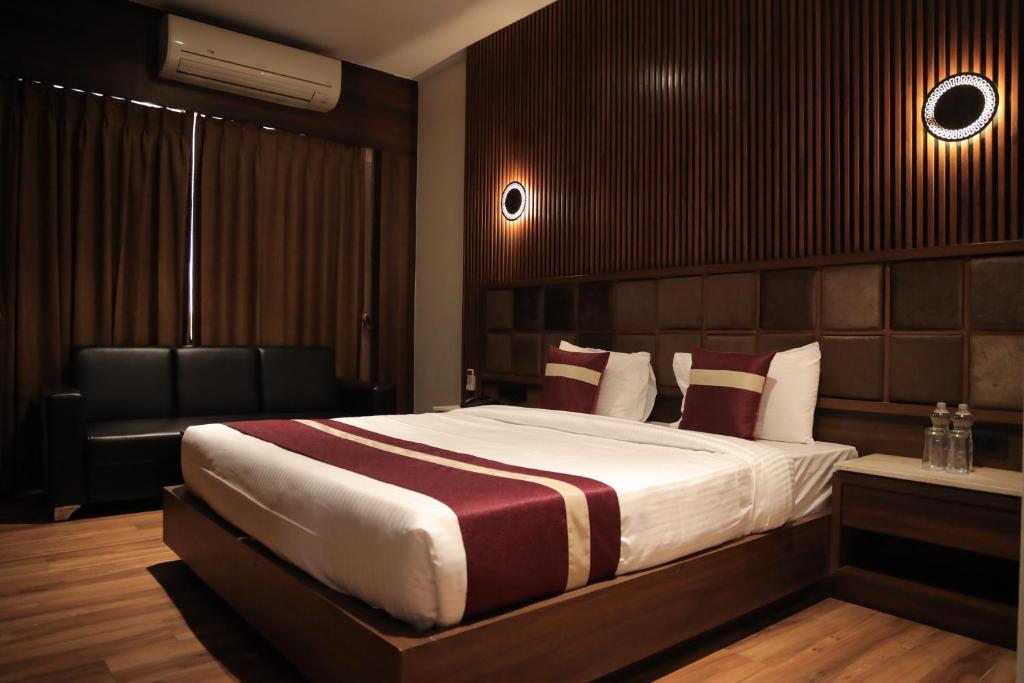 a bedroom with a large bed and a chair at Vivotel Hotel Surat in Surat