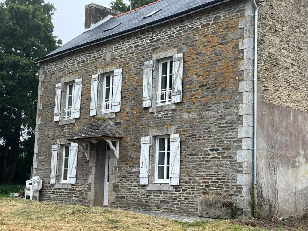 un ancien bâtiment en briques avec des fenêtres blanches et une porte dans l'établissement Grande Maison de Campagne proche de Carhaix, à Plévin
