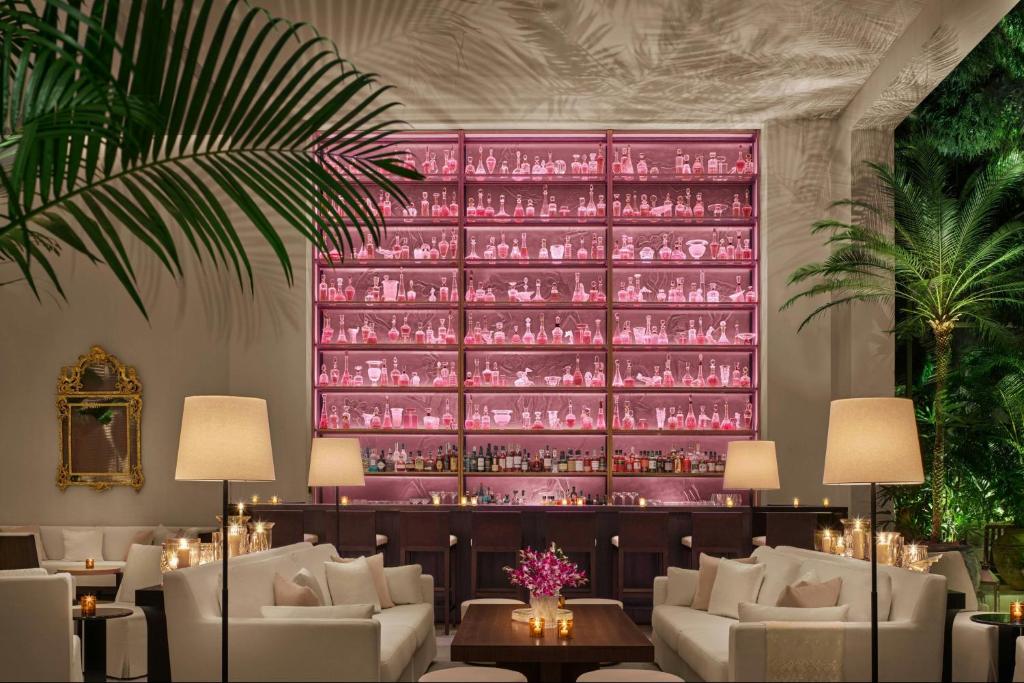 Uma sala com sofás e uma grande parede repleta de taças de vinho. em The Singapore EDITION em Singapura