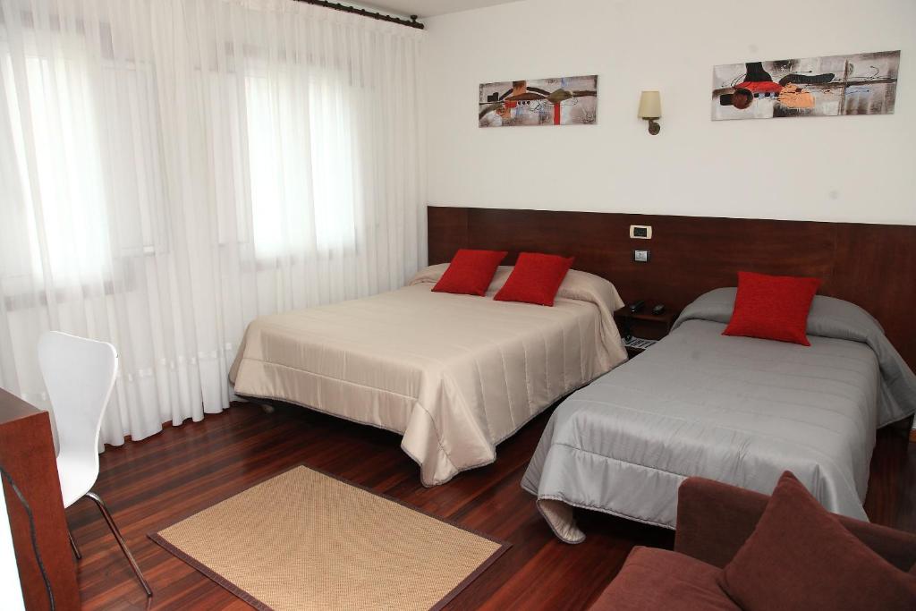 Habitación con 2 camas y almohadas rojas. en Hotel Restaurante Rúas en Pontevedra