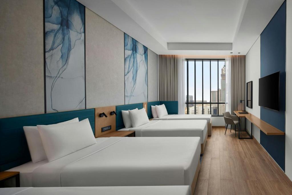 メッカにあるCourtyard by Marriott Makkahのベッド3台とテレビが備わるホテルルームです。