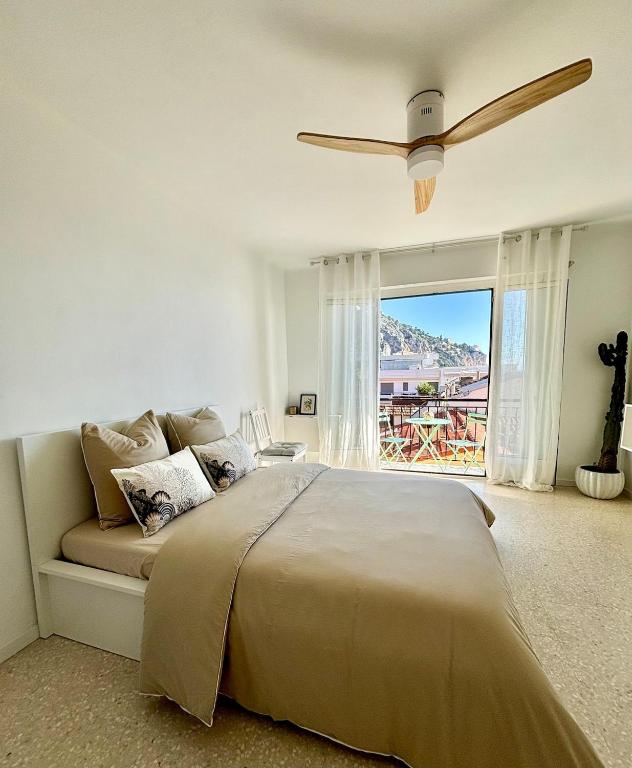 une chambre avec un lit et un ventilateur de plafond dans l'établissement Sea View Studio with Balcony, Near Italy & Monaco, à Menton