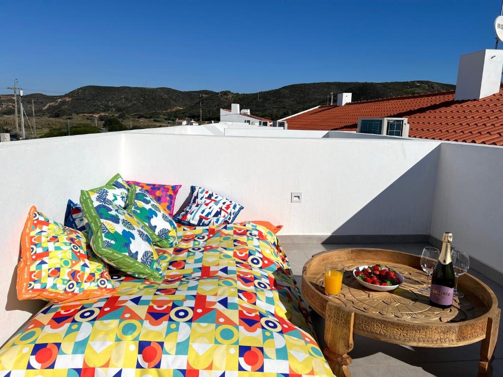 a bed with pillows and a table on a balcony at Casa Cordoama in Bordeira