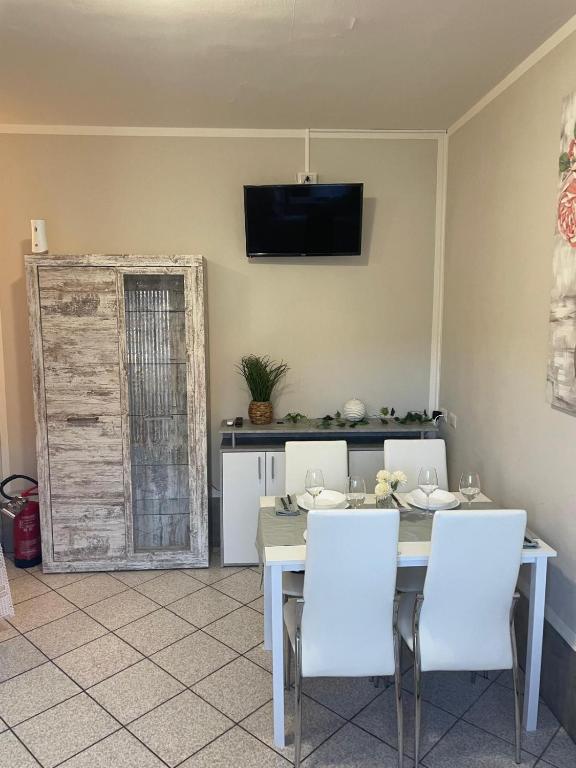 a dining room with a table and white chairs at Bnbook Lago Magico in Dormelletto