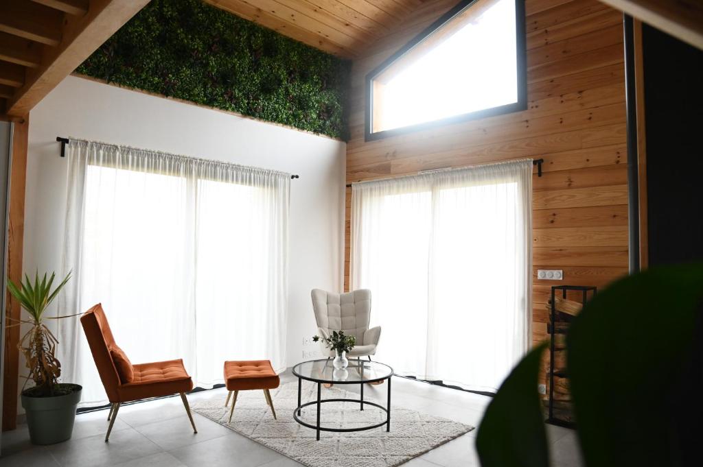 Saint-YaguenにあるPinéa Lodge - Chalet Authentique en Pin des Landesのテーブルと椅子と窓のあるリビングルーム