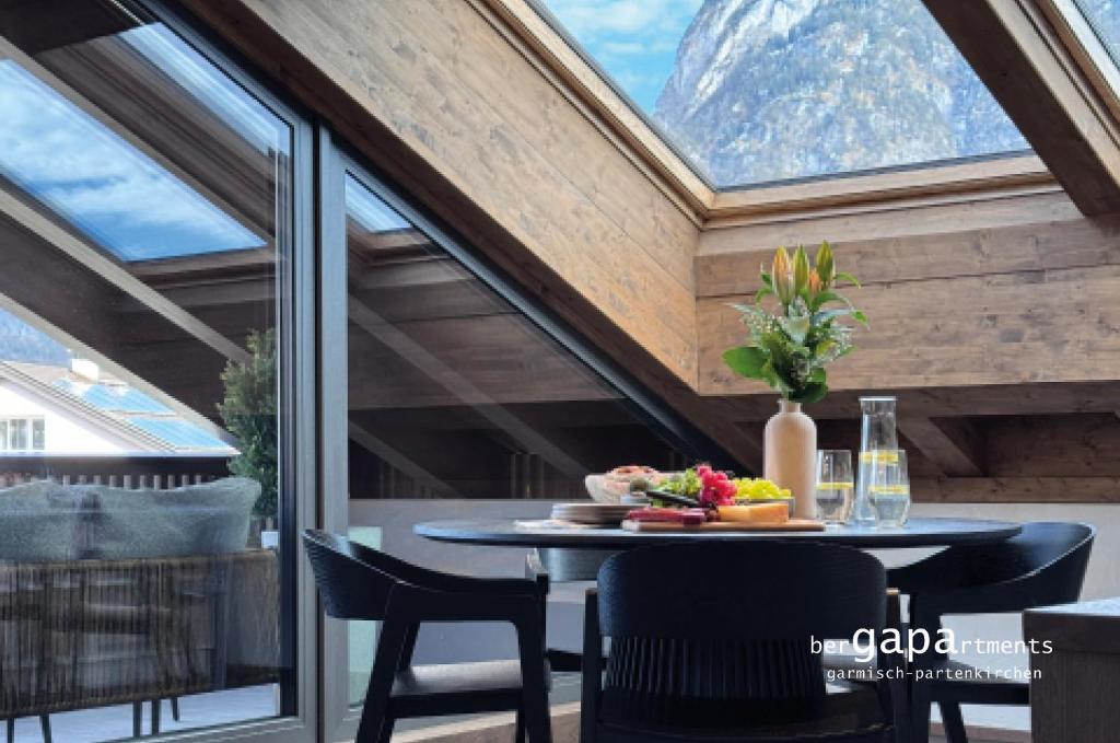 een eetkamer met een tafel en stoelen en een raam bij BergVibes in Garmisch-Partenkirchen