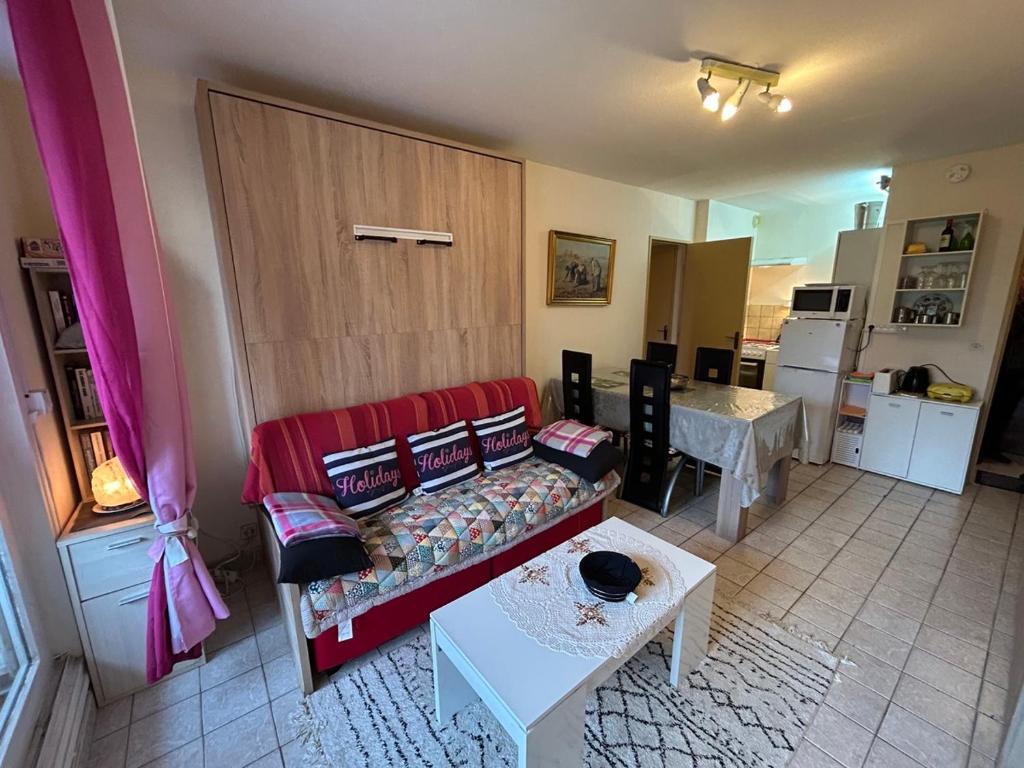 un salon avec un canapé rouge et une table dans l'établissement Plaisir a la mer c, à Courseulles-sur-Mer