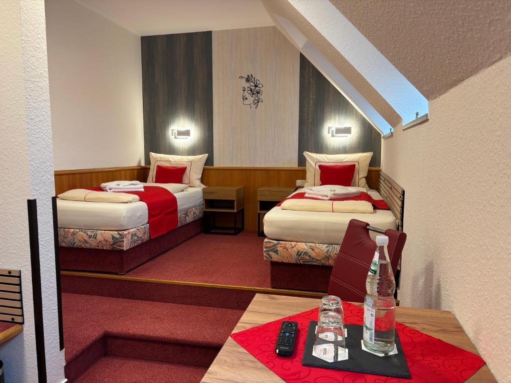una camera d'albergo con due letti e un tavolo di Ambiente Hotel Strehla a Strehla