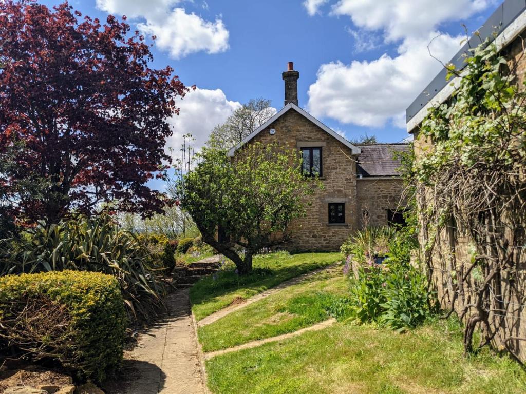 an old stone house with a garden in front of it at Keeper’s Cottage in Montacute