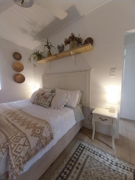 ein Schlafzimmer mit einem Bett und einem Tisch mit einer Lampe in der Unterkunft Mountain View - The Little Gem in Montagu