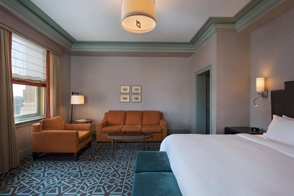a hotel room with a bed and a couch and chairs at Hotel ICON, Autograph Collection in Houston