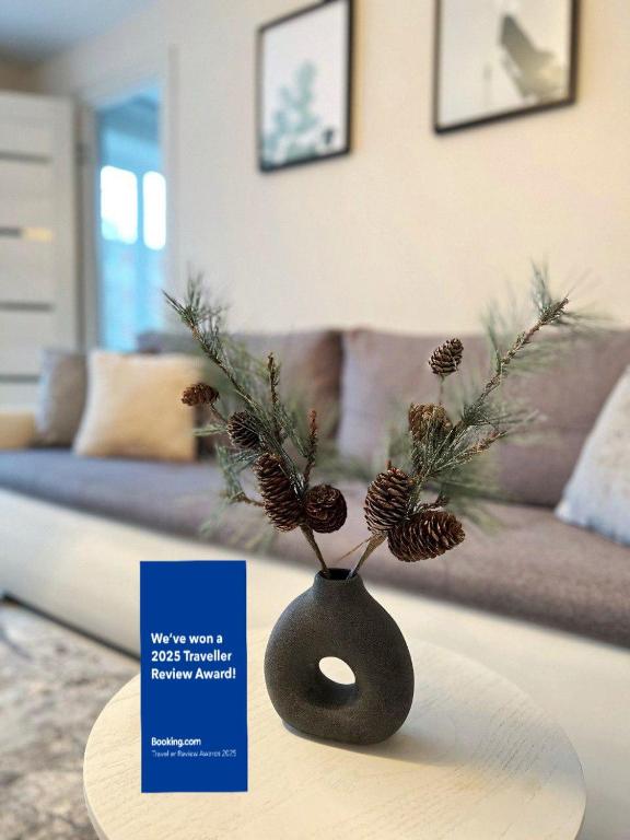 a vase with pine needles and a card on a table at New Modern Apartments in the City Center in Narva