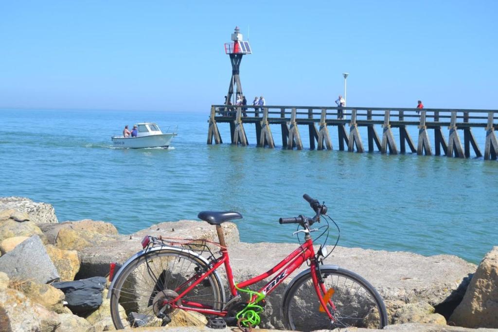 un vélo rouge garé sur les rochers près d'une jetée dans l'établissement Plaisir a la mer B, à Bernières-sur-Mer