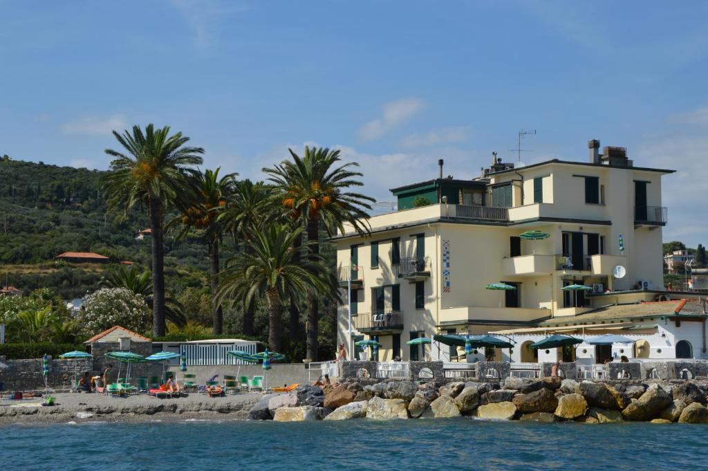 un grande edificio sulla spiaggia con palme di Residence Villa Miky ad Albenga