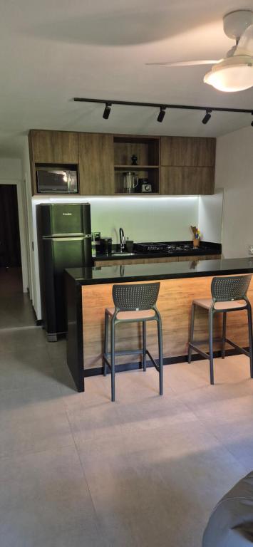 - une cuisine avec 2 chaises et un comptoir avec évier dans l'établissement Flat Moderno Pé na Areia no Cumbuco Piscina e Localização Perfeitas Eco Paradise, à Caucaia