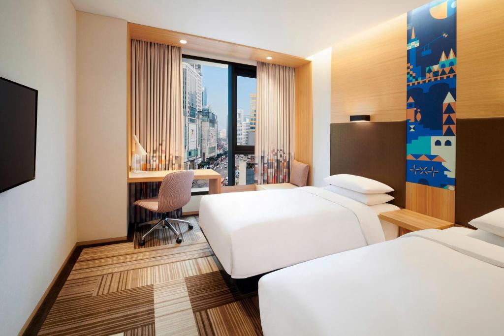 a hotel room with two beds and a desk at Aloft Seoul Myeongdong in Seoul