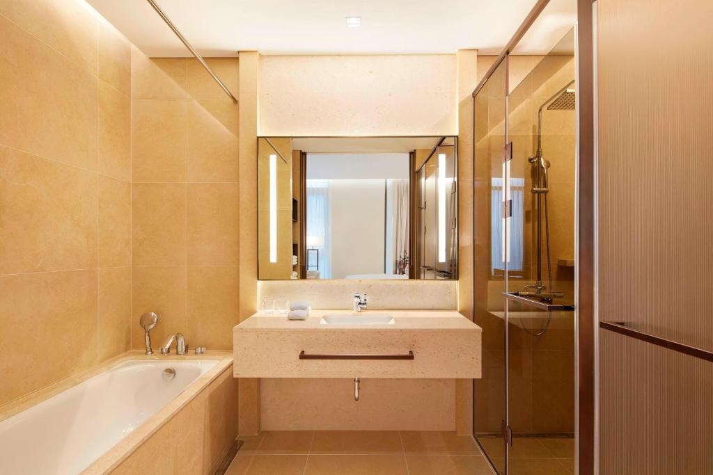 a bathroom with a sink and a tub and a mirror at Aloft Seoul Myeongdong in Seoul