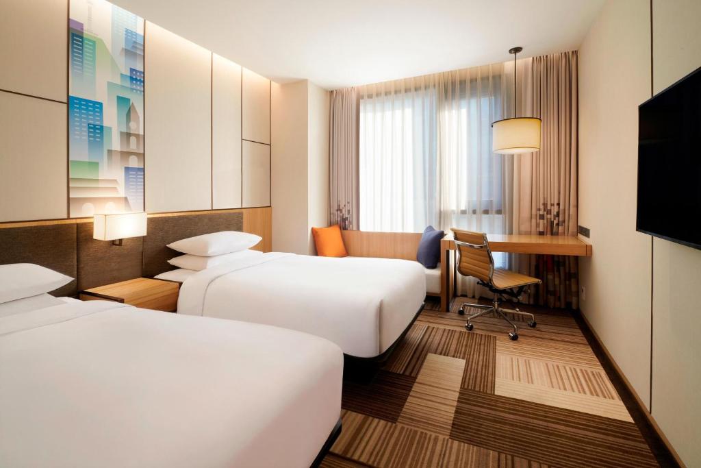 a hotel room with two beds and a desk at Aloft Seoul Myeongdong in Seoul