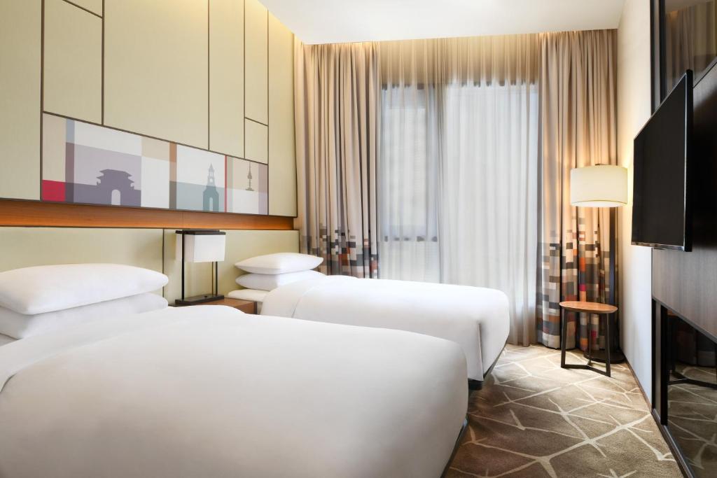 a hotel room with three beds and a television at Aloft Seoul Myeongdong in Seoul
