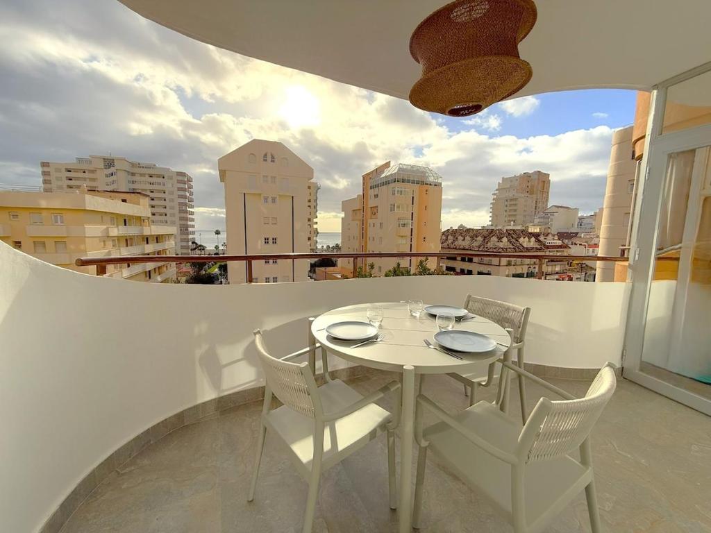 a table and chairs on a balcony with a view of a city at Modern & sunny beach apartment in Fuengirola