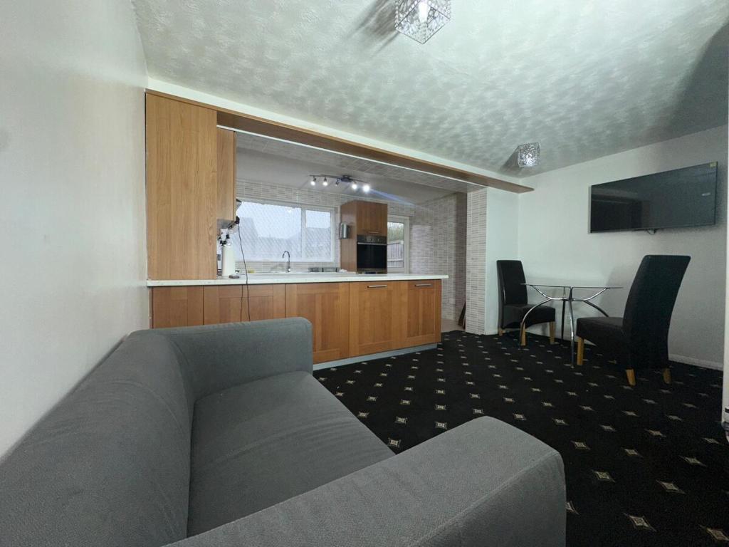 Una sala de estar con un sofá y una cocina. en 3 Bedroom House Available, en Hounslow