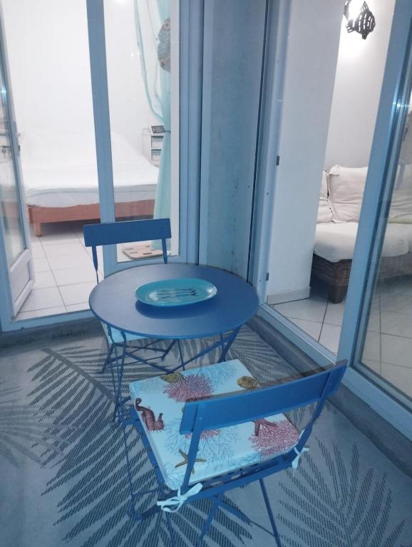 2 chaises et une table bleue dans une pièce dans l'établissement T2 atypique côté Brassens, à Sète