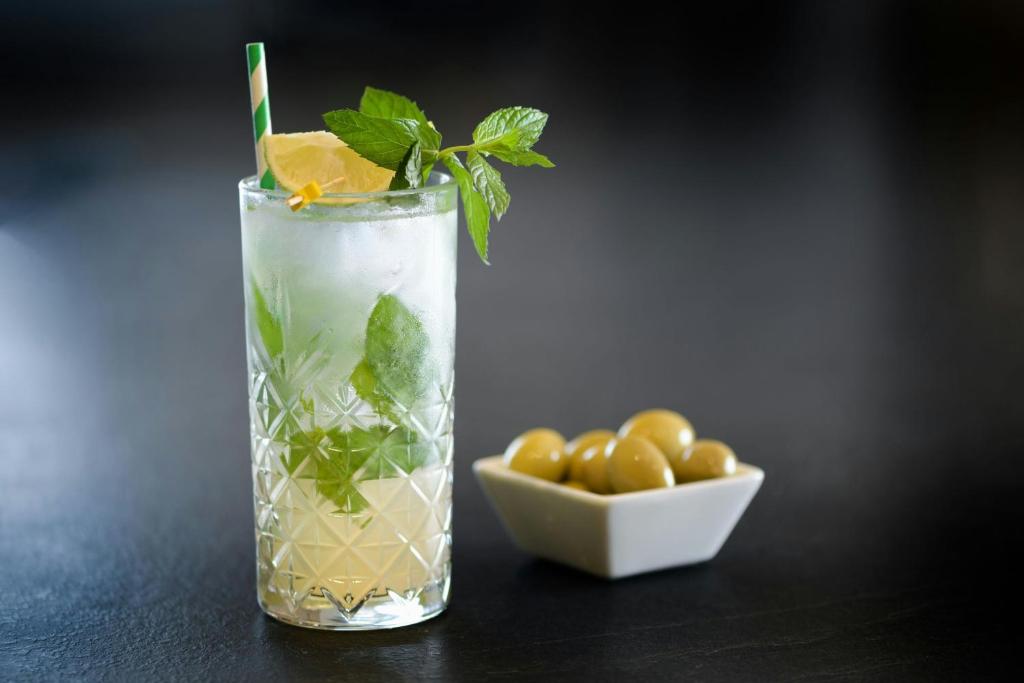 a drink with mint and lime and a bowl of olives at AC Hotel Venezia by Marriott in Venice