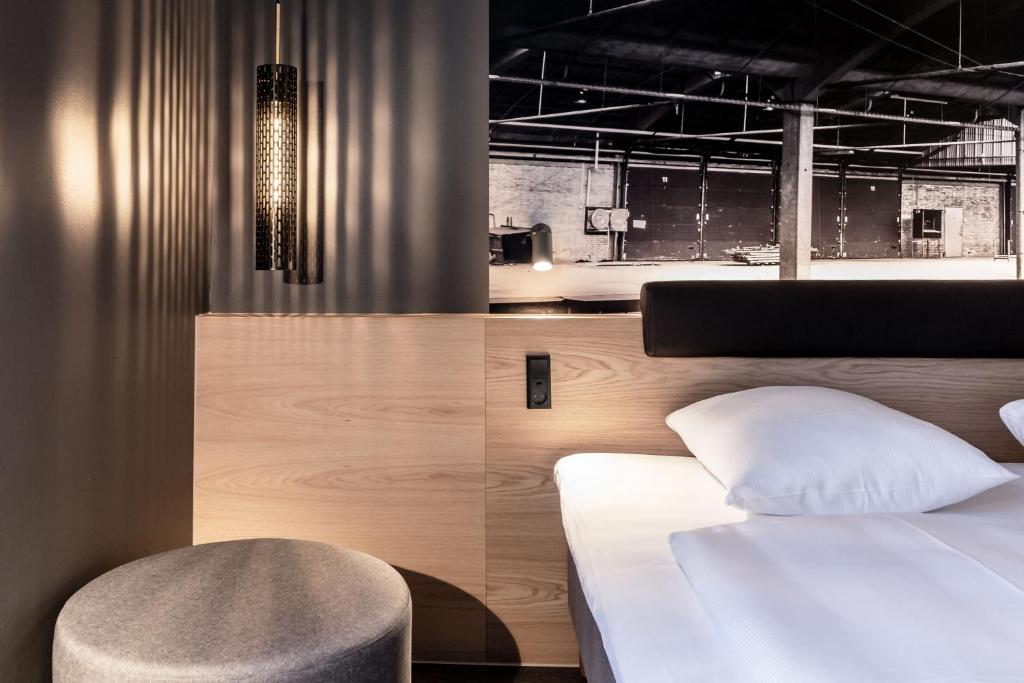 um quarto com uma cama branca e uma cadeira em Four Points Flex by Sheraton Aalborg em Aalborg