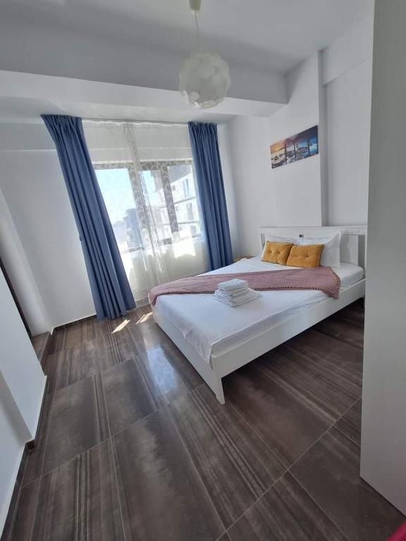 a bedroom with a large bed with blue curtains at By the Sea Plusoi Apartment in Năvodari