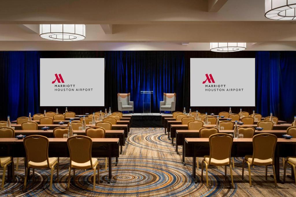 a conference room with tables and chairs and two screens at Houston Airport Marriott at George Bush Intercontinental in Houston