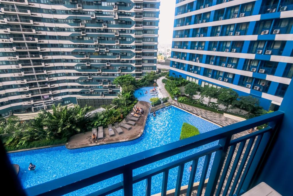 马尼拉Cozy Peacock hideaway Stylish Makati Condo 300 Mbps Gym Swim Park的阳台享有泳池美景,设有建筑