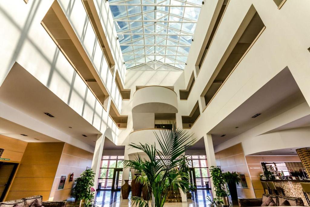 a large lobby with a glass ceiling and plants at Alcalá Plaza in Alcalá de Henares