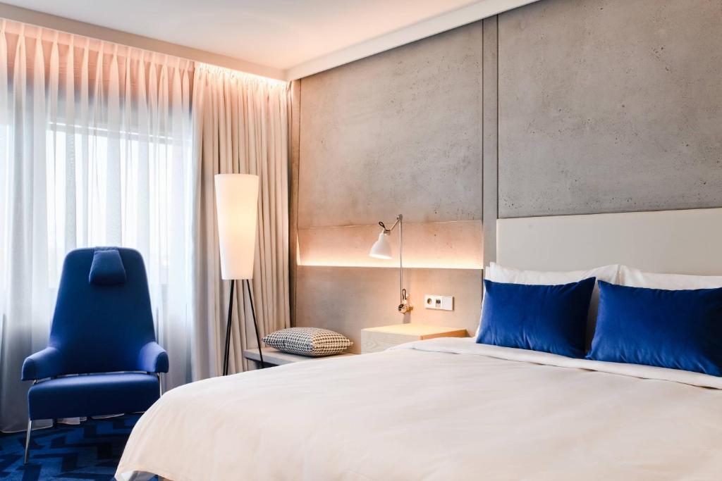 a bedroom with a large bed and a blue chair at Renaissance Warsaw Airport Hotel in Warsaw